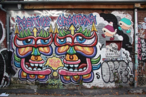 A positive creation by Chris Dyer and two wheatpastes by Turtle Caps (top right) in alley between St-Laurent and Clark